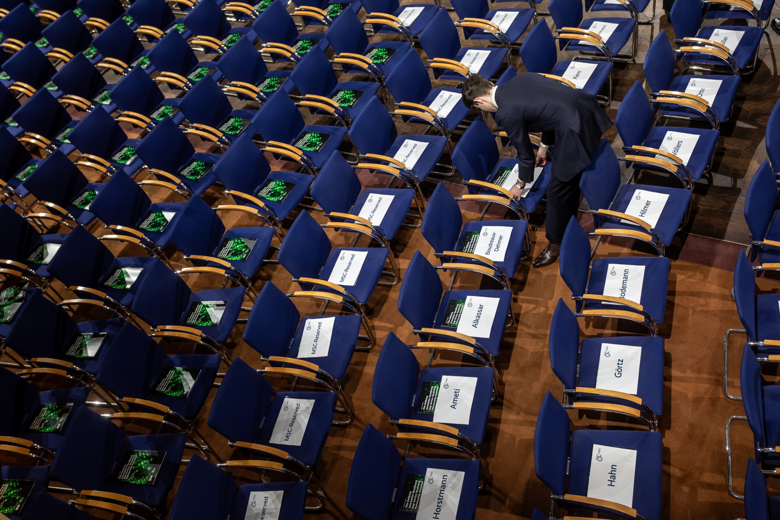 20240215 MSC, Munich Security Conference, Bayerischer Hof: An individual arranges conference materials on seats in a large hall, preparing for the attendees of the 60th Munich Security Conference. Photo: Karl-Josef Hildenbrand/MSC